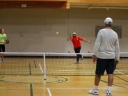 Three people playing pickleball