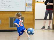 Little girl kicking soccer ball and a coach at Start Smart Soccer