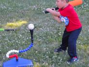 Child with bat hitting a wiffle ball at Start Smart Tee Ball