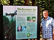 Former Parks and Recreation Director Galen McBee Standing Next to the Galen McBee Airport Park Sign