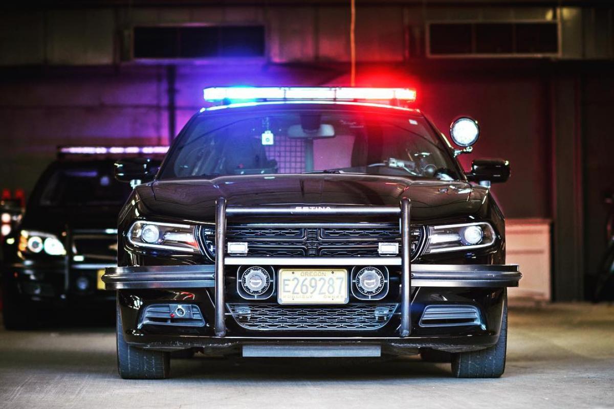 Image of front facing police car with blue and red lights turned on.