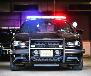 Image of front facing police car with blue and red lights turned on.